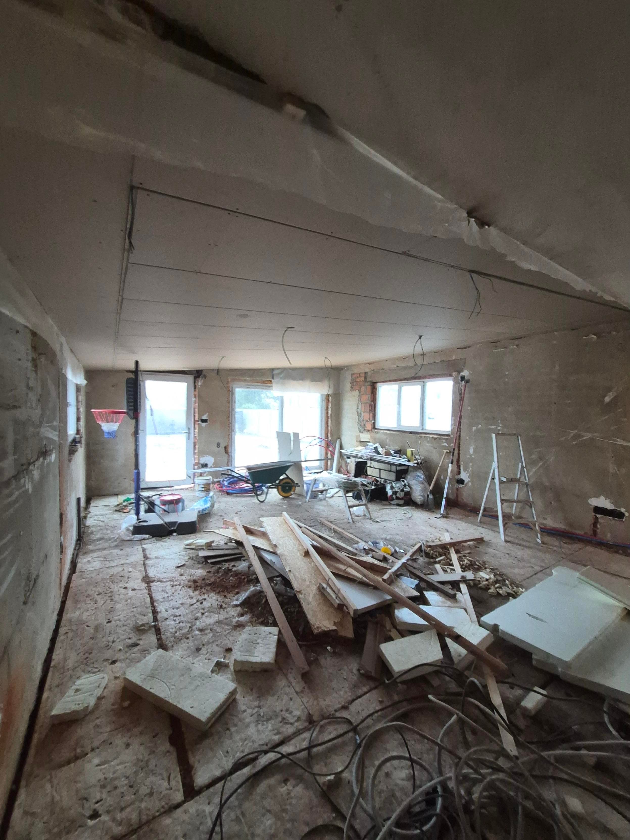 Unfinished room under renovation filled with wood debris, construction tools, and tangled electrical wiring.